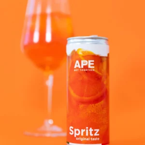 Image of a can of spritz in the foreground and a glass of spritz in the background. The background is light orange, matching the colors of the can's graphics.